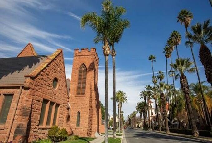 A church surrounded by palm trees, with a street visible in front, creating a serene and inviting atmosphere.